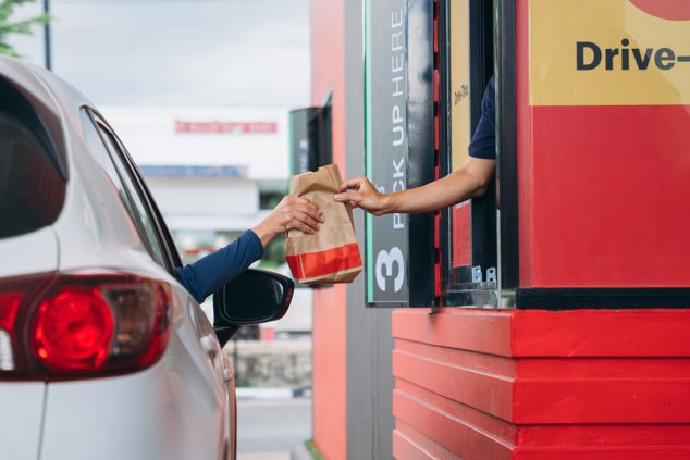 Cropped photo of drive-thru working handing food bag to customer