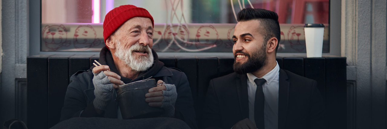 Photo of homeless man spending time with well dressed man