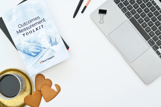 Photo of desk with True Charity Outcomes Measurement Toolkit and office items