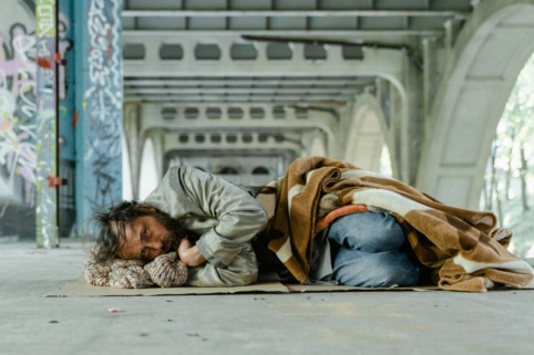 Photo of homeless man resting under bridge