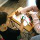 Photo of child and daycare ministry worker drawing with crayons together.
