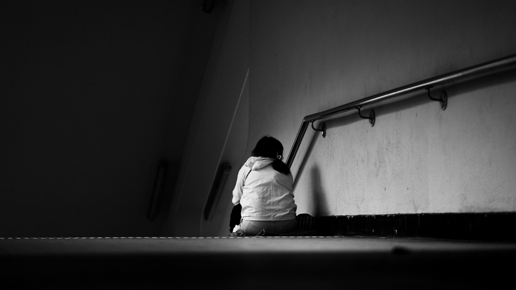 Black and white photo of woman sitting alone in stairwell